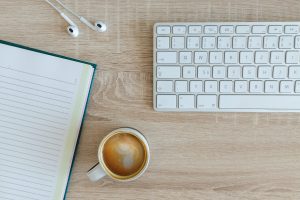 coffee latte near white wireless keyboard and Apple EarPods on the table photography